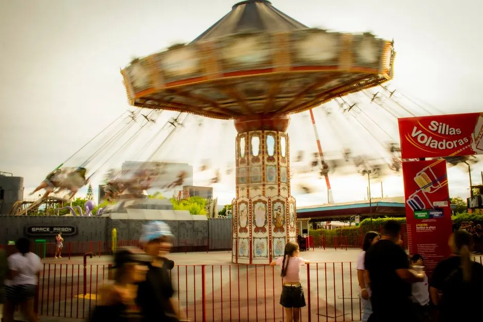 Blurred motion of a swing ride in an amusement park with people watching.