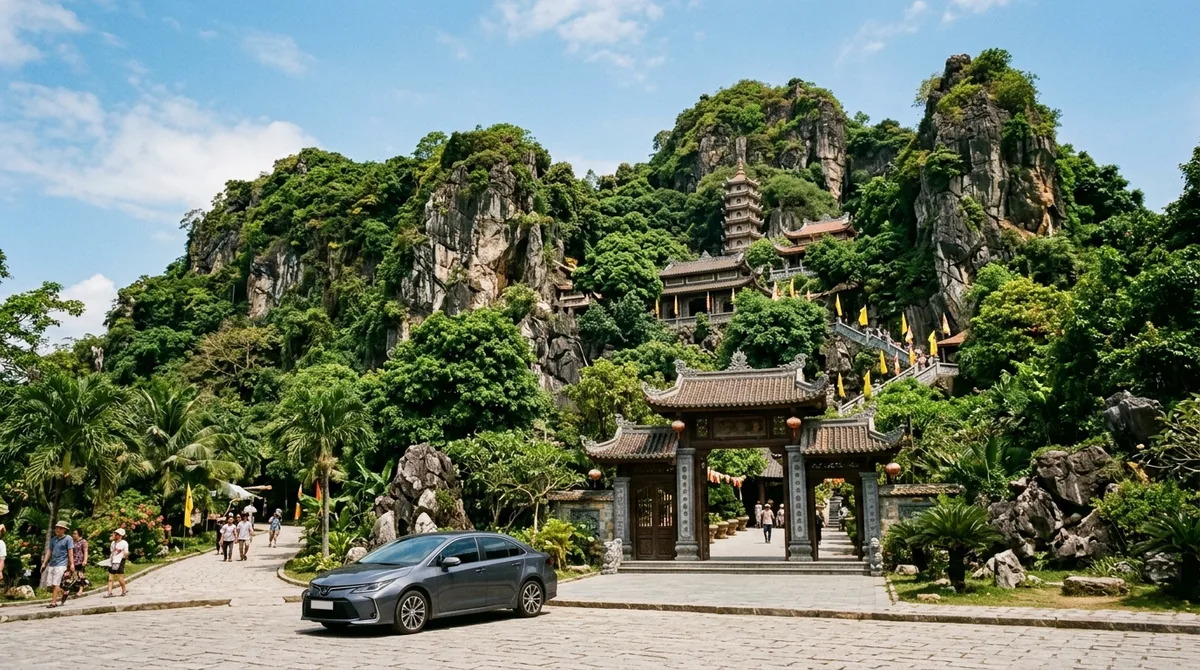 Xe sedan đỗ trước cổng Ngũ Hành Sơn Đà Nẵng với chùa và tháp trên vách núi đá